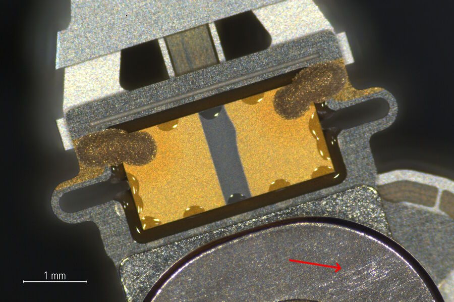 [Translate to chinese:] Zoom-in of the indicated area in Fig. 3a showing more detail of the same hard drive read-write head and actuator arm. There are scratches on the arm’s metal surface near the head (arrow).