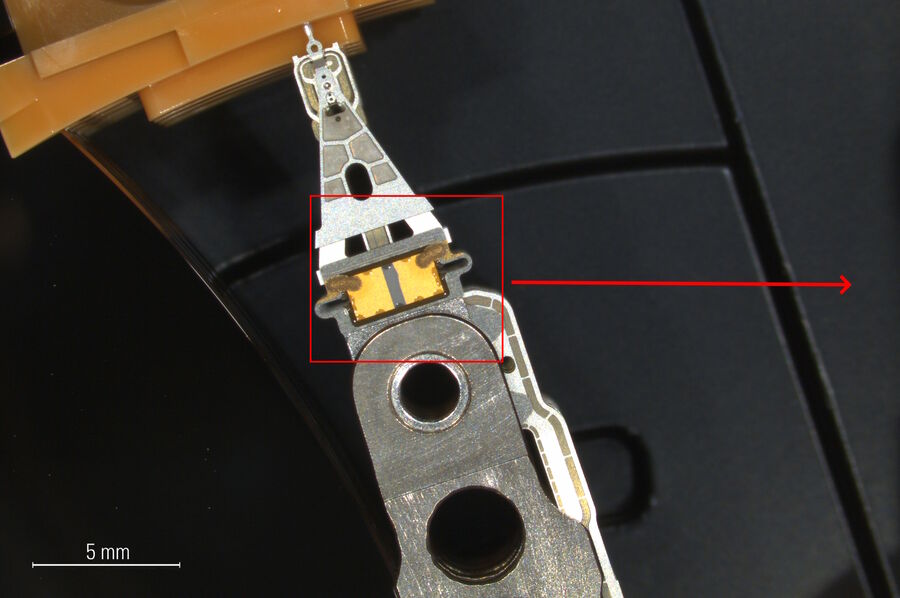 [Translate to chinese:] Image of a hard drive read-write head and actuator arm at lower magnification.