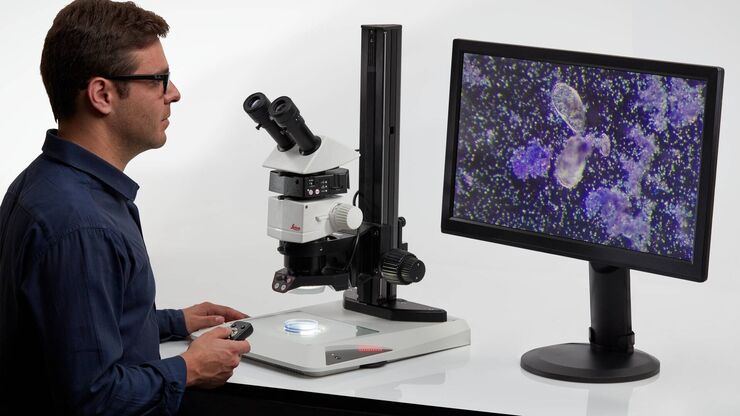 Man infront of a microscope and a screen