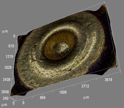 Multi-focus image in 3D of a brass cartridge case showing the firing pin mark on the primer.